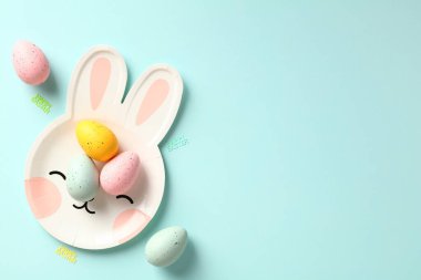 Pastel mavi arka planda renkli Paskalya yumurtaları olan tavşan şekilli tavşanlı Paskalya bayramı kompozisyonun kutlu olsun. Düz konum, üst görünüm, kopyalama alanı.