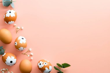 Mutlu Paskalyalar. Paskalya yumurtaları ve pastel pembe arka planda bahar çiçeklerinden yapılmış çerçeve. Düz konum, üst görünüm, kopyalama alanı.