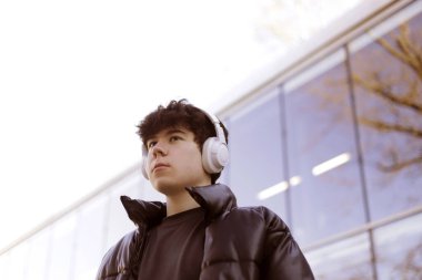 Kulaklıklı bir çocuğun açık havada çekilmiş fotoğrafı.