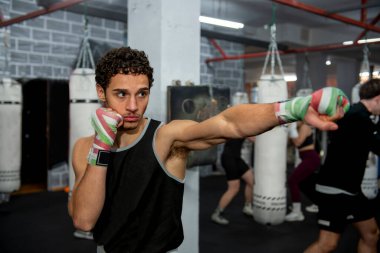 Genç bir boksör, boks salonunda kendini adamış ve gücünü sergiliyor.