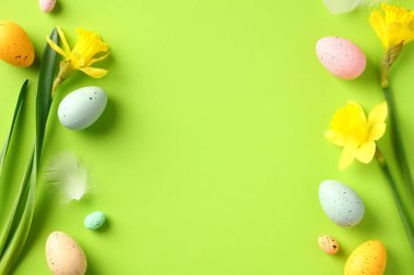 Mutlu Paskalya tebrik kartı şablonları. Renkli Paskalya yumurtaları ve yeşil masadaki sarı nergis çiçeklerinden yapılmış çerçeve..