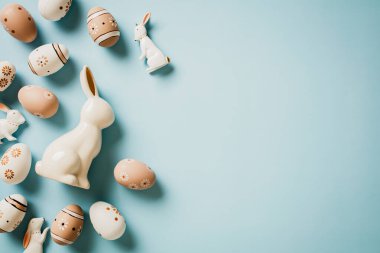 Çiçeklerle süslenmiş Paskalya yumurtaları, pastel mavi arka planda dekoratif Paskalya tavşanları. Üst Manzara. Düz yatıyordu.