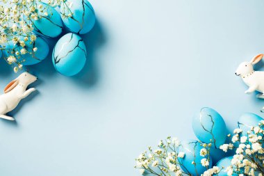 Paskalya posteri ve boyanmış Paskalya yumurtaları, bahar çiçekleri, pastel mavisi arka planda bir tavşan..