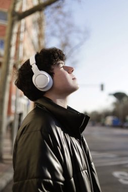 Kulaklıklı ve gözleri kışın güneşe bakan bir adam.