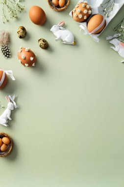 Mutlu Paskalya bayrağı tasarımı. Süslü yumurtalar, beyaz seramik tavşanlar, tüyler ve pastel yeşil arka planda çiçeklerle bezenmiş düz bir kompozisyon.