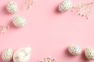 Renkli Paskalya yumurtaları, tavşancık ve bahar çiçekleri pastel pembe arka planda yatıyordu. Yukarıdan görüntüle, boşluğu kopyala.