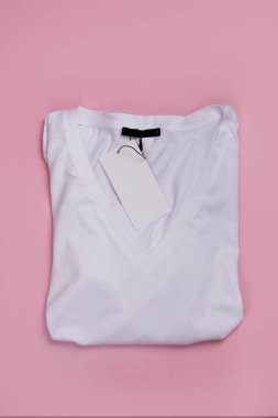 Üzerinde pembe arkaplan etiketi olan beyaz V yaka tişörtün üst görünümü