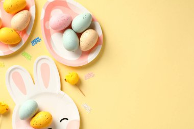 Tatlı tabaklar üzerinde renkli Paskalya yumurtaları ile mutlu Paskalya kompozisyonu.