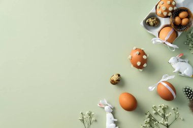 Paskalya yumurtalarıyla, seramik tavşanlarla, pastel yeşil arka planda çiçek dallarıyla bezenmiş.