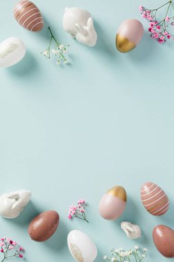 Paskalya yumurtaları, tavşanlar, pastel mavi arka planda çiçekler ile Mutlu Paskalya bayrağı tasarımı.