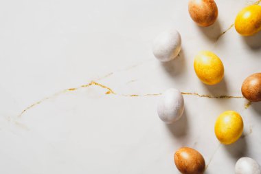 Altın Paskalya yumurtaları mermer masanın üzerine bırakılmış. Kopyalama alanı olan üst görünüm.