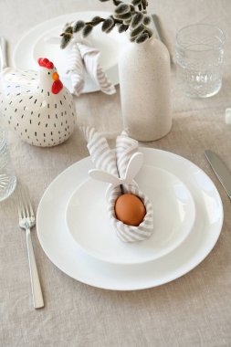 Paskalya sofrasında tavşanlı peçeteyle paskalya yumurtası ve çatal bıçak takımı..