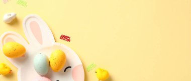 Tavşan tabağı ve sarı arka planda renkli Paskalya yumurtaları olan mutlu Paskalya afişleri..