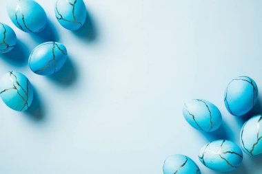 Mavi arka planda boyanmış Paskalya yumurtaları çerçevesi. Zarif Paskalya kartı şablonu. Düz konum, üst görünüm, kopyalama alanı.