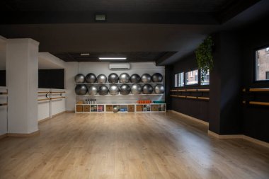 Modern spor salonu, pilates topları, ahşap parmaklıklar ve çeşitli egzersiz aletleri, antrenman için hazır.