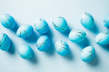 Mavi Paskalya yumurtaları açık mavi arka planda mermer dokuya boyanmış. Düz yatış, üst görünüm.