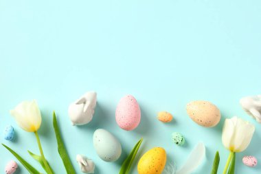 Pastel mavi arka planda Paskalya yumurtaları ve laleler. Mutlu Paskalyalar. Düz yatış, üst görünüm.