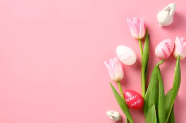 Paskalya bayrağı tasarımı. Renkli Paskalya yumurtaları, pembe arka planda laleler. Üst manzara, düz uzanma.