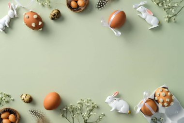 Mutlu Paskalyalar. Süslü Paskalya yumurtaları, bıldırcın yumurtaları, çingene çiçekleri, Paskalya tavşanı, pastel yeşil masadaki tüyler....