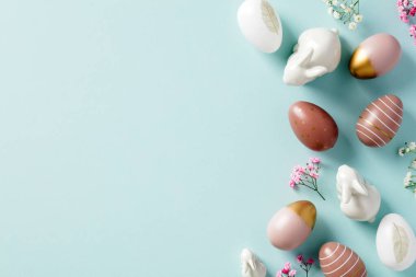 Mutlu Paskalya tebrik kartı şablonları. Renkli Paskalya yumurtaları, minimalist çiçekler, pastel mavi arka planda dekoratif tavşanlar. Düz yatış, üst görünüm.