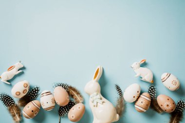 Doğal çiçekli yumurta, tüy, pastel mavi masadaki tavşanlar. Düz yatıyordu. Üst görünüm.