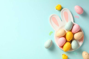 Mavi arka planda renkli Paskalya yumurtaları olan Paskalya tavşanı şeklinde bir tabak. Mutlu Paskalya tebrik kartı şablonu.