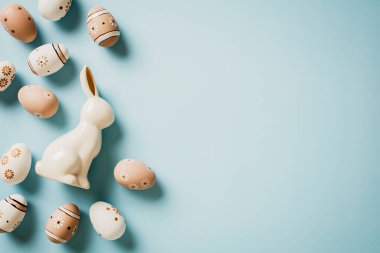 Zarif Paskalya kartı. El yapımı Paskalya yumurtaları ve tavşancık pastel mavi arka planda.,