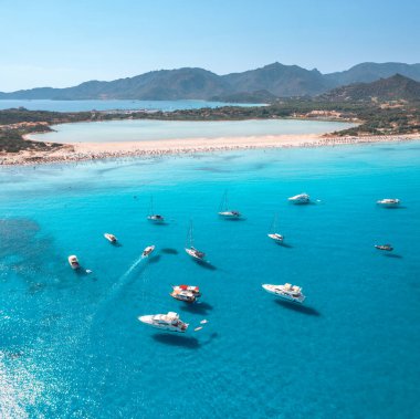 Yazın mavi denizde lüks yatların ve teknelerin hava manzarası. Sardunya, İtalya 'ya seyahat. Sürat tekneleri, yatlar, deniz koyları, beyaz kumlu sahil, dağlar, şeffaf su. Deniz Burnu