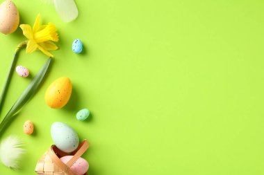 Mutlu Paskalya tebrik kartı maketleri. Paskalya yumurtaları ve yeşil arka planda sarı nergis çiçekleri. Düz konum, üst görünüm, kopyalama alanı