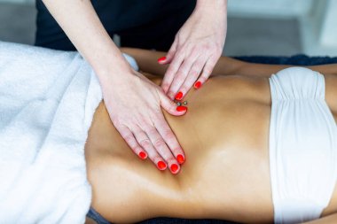 Profesyonel masöz kadın bir müşteriye mide masajı yapıyor. Rahatlamayı ve iyi olmayı teşvik ediyor.