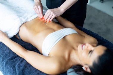 Profesyonel masöz, masaj terapisi sırasında hastasının karnına baskı uyguluyor.