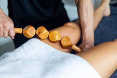 Profesyonel masör tarafından kadının bacağına ahşap bir aletle Maderoterapia masaj tekniği uygulanır.