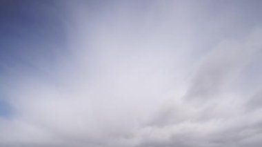 Bulutların zaman çizelgesi dinamik bir şekilde açık mavi gökyüzünde hareket ederek, gökyüzünün dingin ama değişen doğasını yakalıyor..