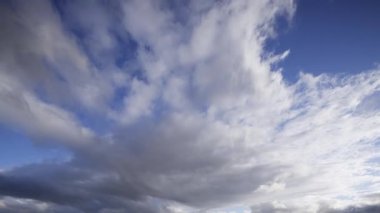Canlı zaman dilimi videosu, bulutların hareketli gökyüzünde dramatik ve hızlı bir şekilde hareket ettiğini gösteriyor. Doğanın güzelliğini ve dinamizmini vurguluyor..
