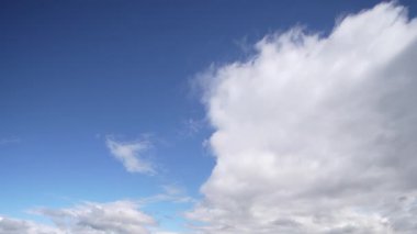 Zaman çizelgesi, bulutların canlı, mavi bir gökyüzünde sürüklenişini gösteriyor. Atmosferin akışkanlığını ve geçici doğasını vurguluyor..