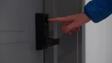 Kırpılmış, tanınmayan birinin eli kart ve parmak iziyle donatılmış anahtarsız, modern bir otel odası kapısını açmak için uzanıyor.