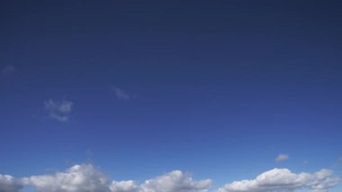 Bulutların hızlı bir şekilde mavi gökyüzüne doğru hareket ettiğini gösteren ve hızlı hareket eden hava koşullarının güzelliğini gösteren bir zaman kaydıyla..
