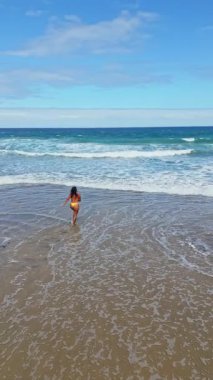 İnsansız hava aracı, Fuerteventura Tindaya Sahili 'ndeki okyanus dalgalarında koşan ve zıplayan bir kadının görüntüsünü yakaladı. Doğal manzaranın ve güneşli plaj gününün tadını çıkarıyorum..