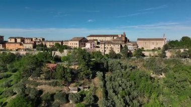 İtalya 'nın Marche bölgesindeki büyüleyici bir kasabanın havadan görünüşü, açık mavi gökyüzü altında tarihi mimari, bereketli yeşillik ve genişleyen manzaralar sergiliyor..