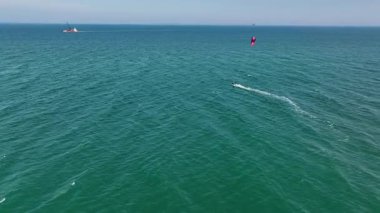 İtalya 'nın Marche bölgesi yakınlarındaki Adriyatik Denizi' nde uçan bir insanın hava görüntüsü. Canlı mavi su, parlak uçurtmayla çelişiyor ve dinamik bir deniz manzarası yaratıyor.