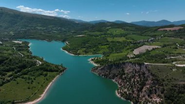İtalya 'nın Marche bölgesindeki gür tepeler ve engebeli uçurumlarla çevrili turkuaz bir göl, berrak mavi gökyüzünün altında, dingin doğal güzellikleri gözler önüne seriyor..