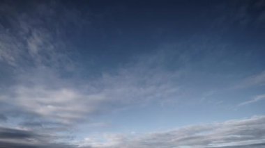 Geniş açılı bir zaman dilimi videosu, bulutların gün ışığından alacakaranlık gökyüzüne kademeli hareketlerini görüntüler, bulutların dinamik ve dinamik doğasını gerçek zamanlı olarak gösterir..
