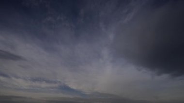 Zaman ayarlı video, gökyüzünde hızla hareket eden zıt siyah ve beyaz bulutların dinamik hareketlerini yakalar, dramatik ve sürekli değişen bir hava sahnesi sunar..