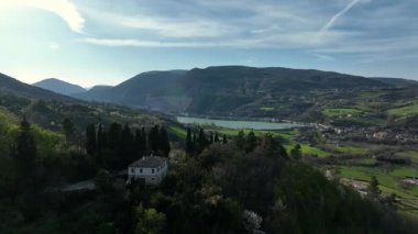 Belforte del Chienti 'nin yemyeşil tepeleri, sakin bir gölü ve berrak bir gökyüzü olan hava manzarası. İtalyan Marş bölgesinin kalbinde huzurlu bir kır manzarası