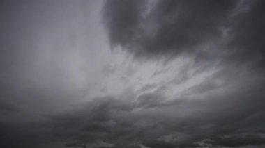 Fırtınalı gökyüzü, bükülen ve sallanan bulutlar ufukta dolaşırken, gerilim ve gizem hissi uyandırıyor.