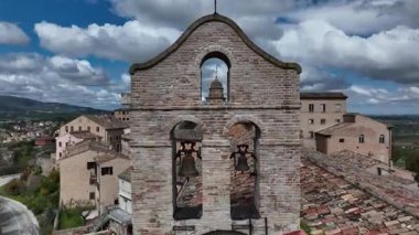 İtalya 'nın orta kesimindeki Treia kasabasındaki çatılar ve tuğla binalarla çevrili tarihi çan kulesinin insansız hava aracı görüntüsü.