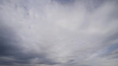 Zaman ayarlı video, gökyüzünde hızla hareket eden zıt siyah ve beyaz bulutların dinamik hareketlerini yakalar, dramatik ve sürekli değişen bir hava sahnesi sunar..