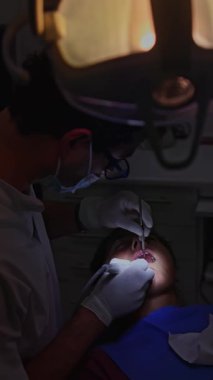 Bir diş hekimi, klinikteki bir hastaya diş temizleme prosedürünü dikkatlice uygular ve ağız sağlığı ve sağlığına odaklanır. Hasta rahat ve rahat.