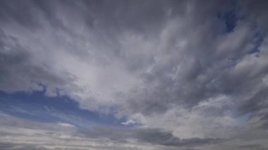 Zaman atlamalı bir videoda kaydedilen dinamik bulut hareketleriyle bulutlu gökyüzü, gerçek zamanlı olarak değişen hava modellerini gösteriyor.