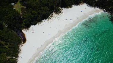 Nefes kesici bir hava aracı görüntüsünde kristal berrak turkuaz suları, yumuşak beyaz kumları ve yemyeşil yeşillikleri olan el değmemiş bir kumsal Avustralya 'nın Jervis Körfezi' nde huzurlu bir sahil cenneti sunuyor..